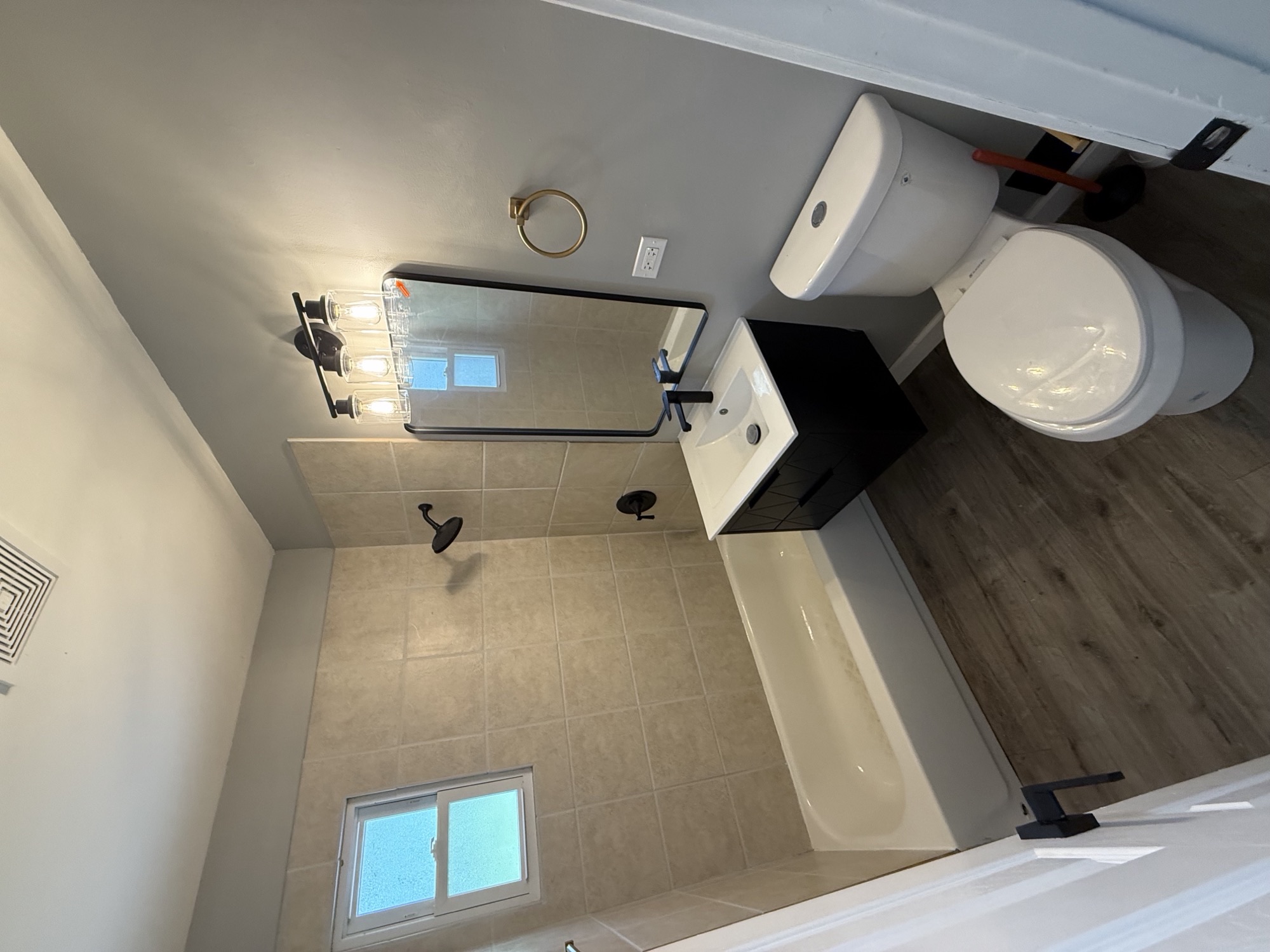 Naperville bathroom after the Lake & Oak update, showing refreshed tile, a vanity, mirror, and lighting